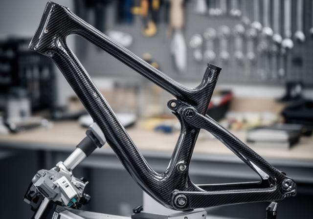 Cuadro de bicicleta de montaña de fibra de carbono apoyado en un taller técnico con herramientas ordenadas y luz suave